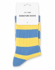 A pair of ribbed knit socks with alternating light blue and yellow horizontal stripes, shown on a white retail hanger card labeled 'EDIT FIVE SIGNATURE SOCKS'. Soft blue and yellow striped socks for women with a warm wool blend, durable construction and flexible stretch fit, ideal for everyday outfits, lounging, winter wear and colourful sock gifts.