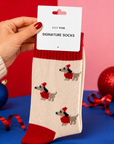 Soft cream novelty dog socks featuring festive dachshunds, bright red details and a cosy wool blend. Fun Christmas gift socks for winter outfits, festive mornings and dog lovers.