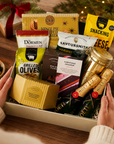 Luxury Christmas champagne gift hamper in a large magnetic gift box featuring two bottles of Moët & Chandon Champagne, Christmas chocolate, grilled olives, snacking cheese, cheddar and shallot crisps, chocolate and orange shortbread, festive nut mix, whisky fudge, mince pie stuffed cookies and Christmas pudding.