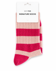 A pair of ribbed knit socks with horizontal stripes in pink and a light peach-beige, attached to a white cardboard hanger card that reads 'EDIT FIVE SIGNATURE SOCKS'. Soft pink striped socks for women with a warm wool blend, durable construction and flexible stretch fit, ideal for everyday outfits, lounging, winter wear and colourful sock gifts.