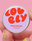 Lip balm container with 'LOVELY' branding on a pink background