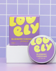 Purple and yellow lip balm with packaging on a tiled background