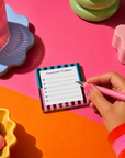 Edit Five 10 x 10cm square memo notepad featuring bold rainbow stripes, playful typography and checklist pages, ideal for organising work tasks, home life, ideas and everyday reminders.