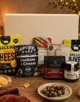 Luxury gourmet gift hamper presented in a premium magnetic gift box featuring cookies and cream popcorn, chilli jam, English Breakfast tea, grilled olives, salted caramel milk chocolate, sweet chilli peanuts and cashews, and snacking cheese.