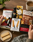 Luxury Christmas letterbox gift hamper featuring Baileys Irish Cream, English Breakfast tea, cinnamon roll popcorn, salted caramel chocolate, zesty lime and chilli peanut and cashew mix, and all-butter shortbread presented in a premium Hallby gift box.