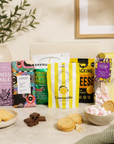 Luxury gourmet gift hamper in a premium magnetic gift box featuring lemon shortbread, cookies and cream popcorn, snacking cheese, limoncello gummies, salted caramel chocolate, red onion relish, cheese sablés and a marshmallow white hot chocolate spoon.