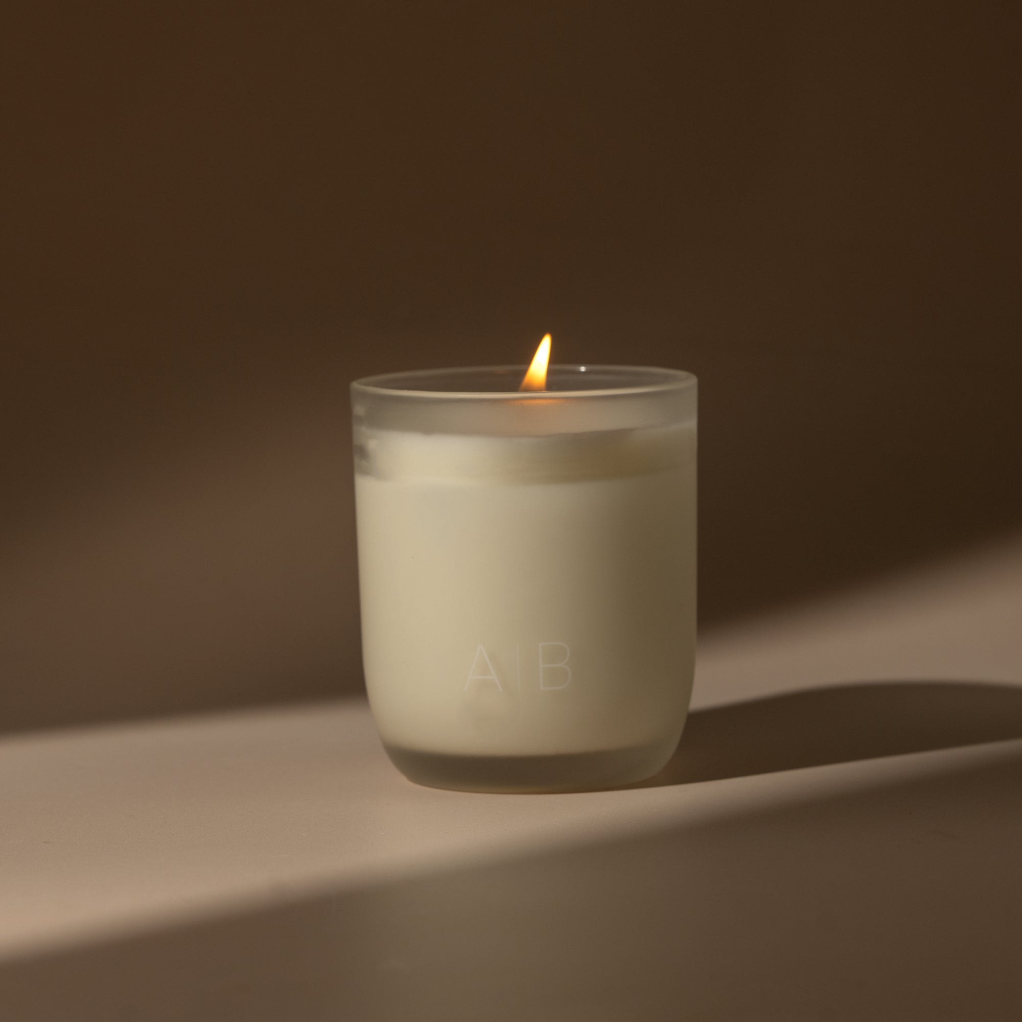 a lit 200g candle featuring a blend of warm amber, refreshing bergamot, tangy orange, sweet vanilla and creamy coconut