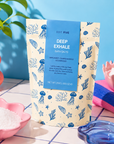 A stand-up pouch of Edit Five Deep Exhale Bath Salts stands on a tiled surface with pink bowls of white salt, a blue towel, and a plant in the background. Gift-ready Deep Exhale aromatherapy bath salts—a cruelty-free self-care gift, relaxation present, pamper-hamper addition or thoughtful wellbeing gift for bath lovers.