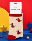 Cream festive dachshund socks featuring sausage dogs in Santa hats and red jumpers, with contrasting red cuffs, heels and toes. dachshund socks, Soft, cosy Christmas socks in UK sizes 4–8.