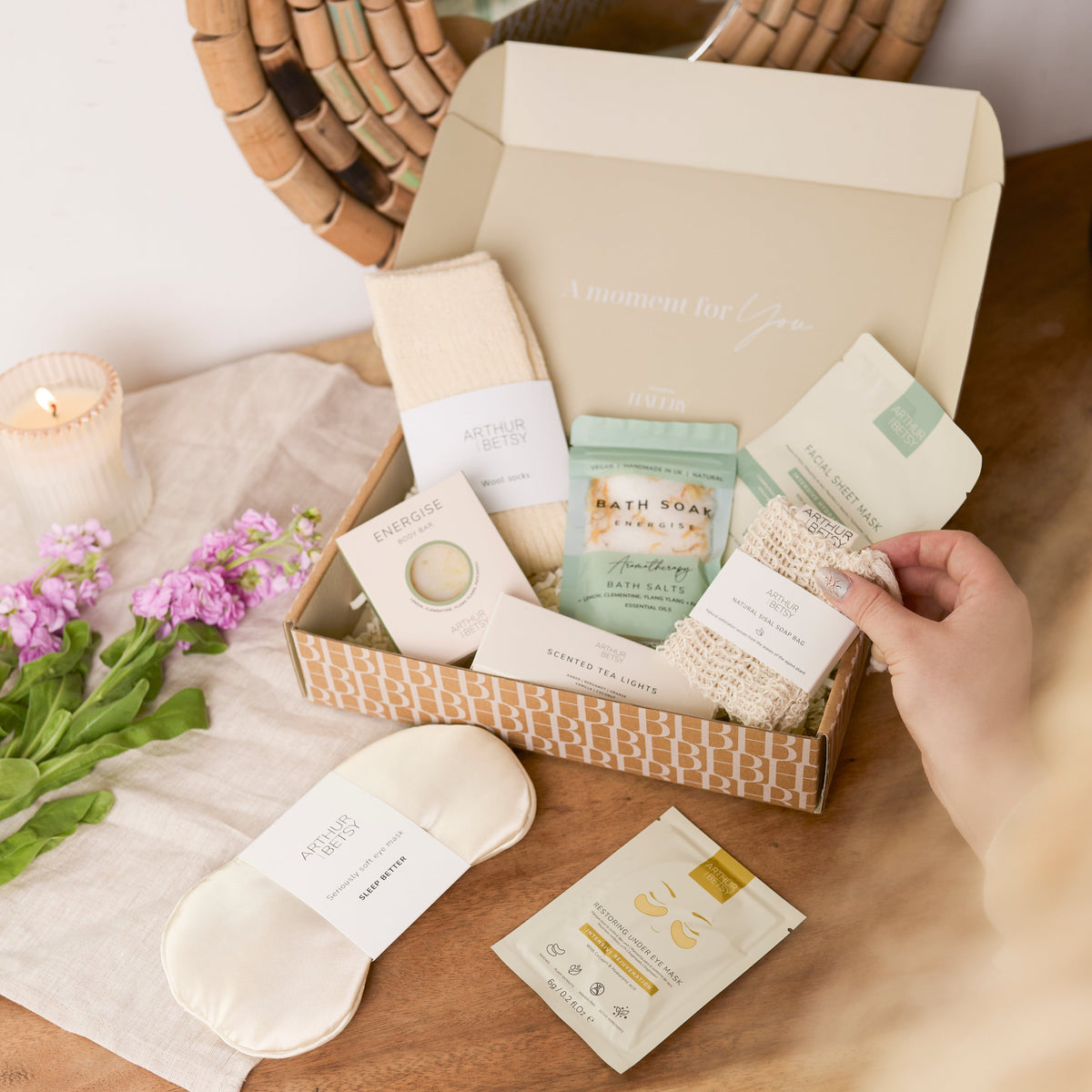 Christmas Retreat gift box from Hallby on a wooden table being unboxed. The gift box contains a sleep mask and various bath products.