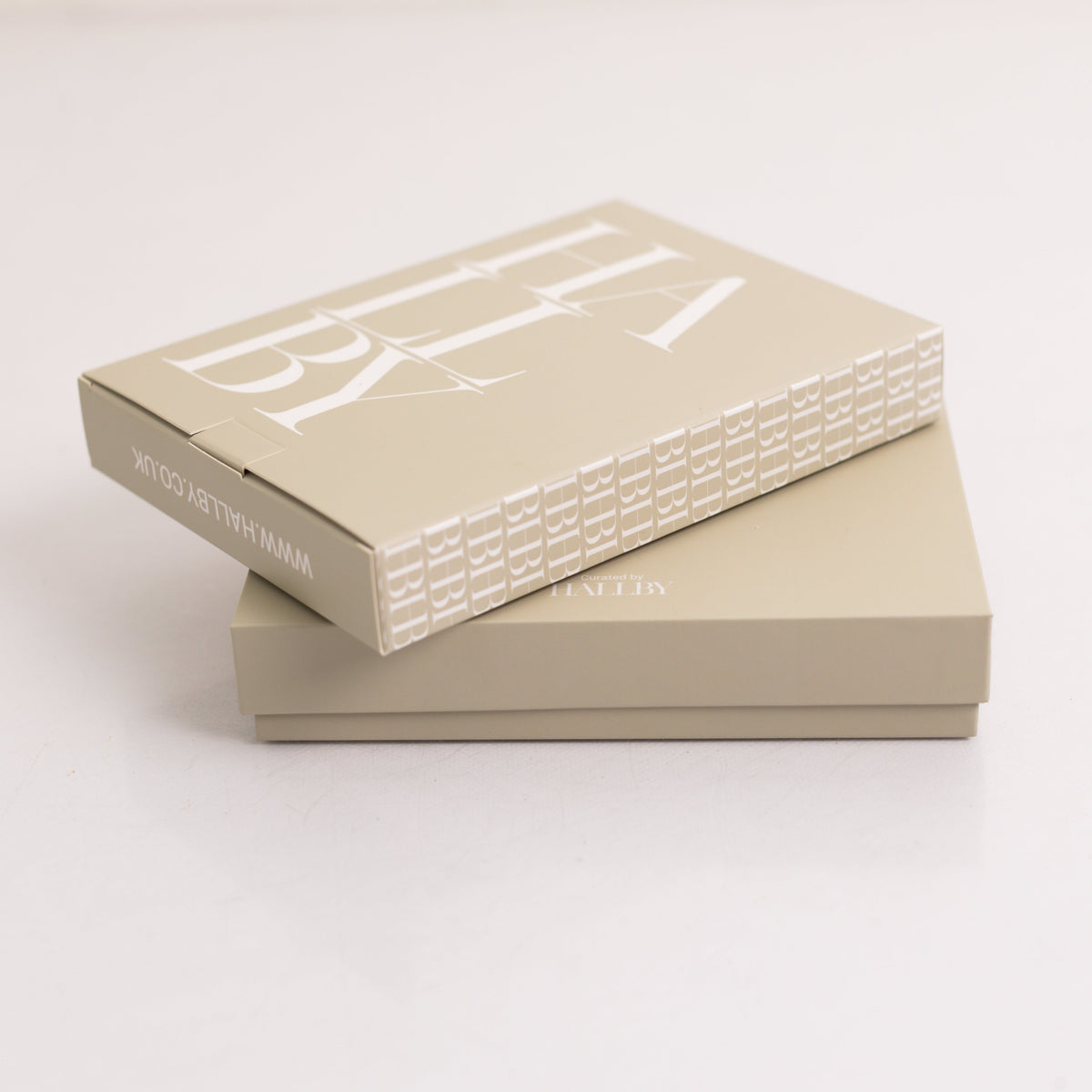 Two stacked beige gift boxes on a clean white background, with the top box angled to show a large white logo and smaller text reading 'HALLBY' on the side.