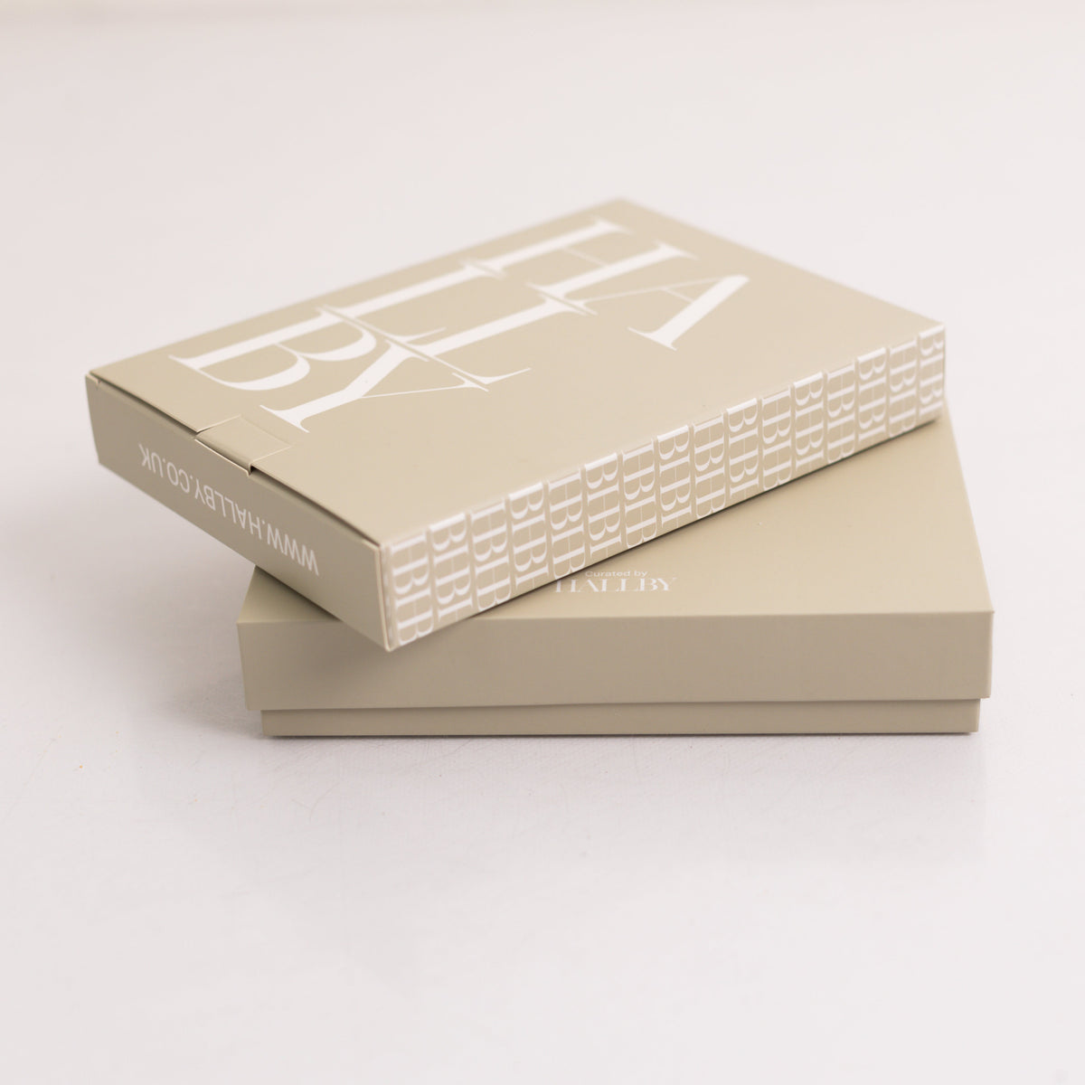 Two stacked beige cosmetic boxes on a clean white background, with the top box angled to show a large white logo and smaller text reading HALLBY on the side.