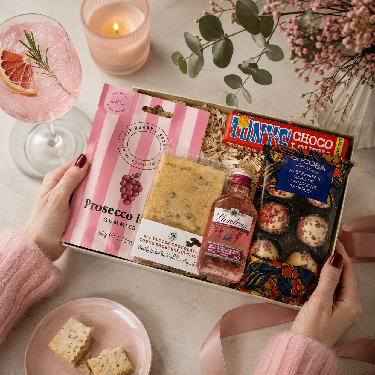 Luxury pink letterbox gift hamper featuring Gordon's Pink Gin, Prosecco Rosé gummies, Tony's Chocolonely milk chocolate, chocolate chunk shortbread slice and raspberry Marc de Champagne truffles presented in a premium Hallby gift box.