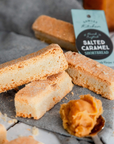 Salted Caramel Shortbread cookies with a spoonful of caramel and a packaging label on a gray surface.