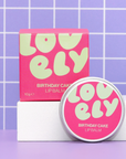 Lovelily Birthday Cake lip balm packaging on a purple grid background