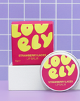 Lovely Strawberry Laces lip balm with packaging on a purple grid background