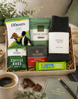 Luxury letterbox self care gift hamper for him featuring wool socks, energising bath soak, English Breakfast tea, coffee bag, pistachio nuts and Tony's Chocolonely dark almond sea salt chocolate in a premium Hallby gift box.